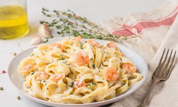 Pasta with shrimps, creamy sauce, parmesan cheese and thyme on a plate. Mediterranean fettuccine with seafood. Italian cuisine. close up